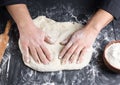 Men`s hands knead a round piece of dough for making pizza