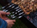 Men`s hands overturn skewers with meat roasted