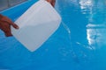 Men`s hands pour light liquid from a plastic tank into a pool, into water. chemical water purification, alkali balance, unsanitar