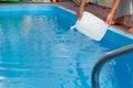 Men`s hands pour light liquid from a plastic tank into a pool, into water. chemical water purification, alkali balance, unsanitar