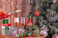 Men's hands pouring champagne from a bottle into champagne flutts against the background of a New Year tree and presents Royalty Free Stock Photo