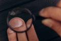 Men`s hands on a rustic black desk holding a magnifying glass. fingerprint examination. palm closeup Royalty Free Stock Photo