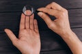 Men`s hands on a rustic black desk holding a magnifying glass. fingerprint examination. palm closeup Royalty Free Stock Photo