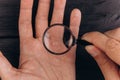 Men`s hands on a rustic black desk holding a magnifying glass. fingerprint examination. palm closeup Royalty Free Stock Photo