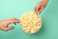 Men`s hands take popcorn from a bucket on background