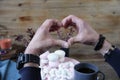 Men`s hands folded in the shape of a heart against the background of pink marshmallow, a cup of coffee an Royalty Free Stock Photo