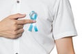 Men`s healthcare concept - close up of male hand pointing to light blue ribbon for prostate cancer at left chest on white Royalty Free Stock Photo