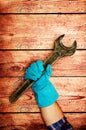 Men`s heavy hand in blue gloves is holding a large old iron key on wooden background