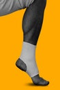 Men`s leg in an elastic bandage on ankle on yellow
