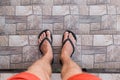 Men`s legs in black flip flops and red shorts go down and walk down the stairs. Walking style Royalty Free Stock Photo