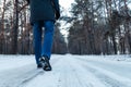 Men`s legs in boots close up the snow-covered path in the winter forest