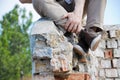 Men's legs in the brown shoes sneakers. Hipster man sitting on the old brick wall outdoor.