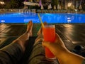 Men`s legs on a deck chair by the pool at night, relaxing with an alcoholic cocktail in a hotel in a warm eastern tropical countr Royalty Free Stock Photo