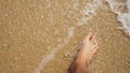 Men`s Legs on the sea sand and wave, Relaxation on the ocean beach, Summer holidays.