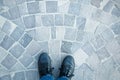 Men`s legs in sneakers and jeans top view on the pavement cobble