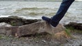 Men`s legs stand on a stone in front of the lake. Flooded stones in the water. Close up of male feet relaxing by the Royalty Free Stock Photo