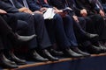 Officials are sitting in the meeting room. Men`s legs in trousers and black shoes. Documents and phones in hand Royalty Free Stock Photo