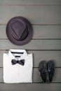 Men's outfit on wooden background. Kids fashion clothes. Grey fedora, white shirt, black bow tie and boat shoes for boy Royalty Free Stock Photo
