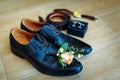 Men`s shoes in black leather, close-up. Wedding concept. Men`s shoes, cufflinks, belt, watch and boutonniere, selective focus