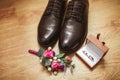 Men`s shoes boutonniere and wedding rings in a box, against the background of a wooden floor. Wedding details.