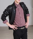 Men`s style. Young fashionable man wearing black leather jacket, denim jeans, checkered shirt and belt