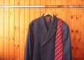 Men`s suit and red striped tie on hanger on wooden background Royalty Free Stock Photo