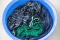 Men\'s t-shirts, jogging pants, and trousers are being washed in a plastic bowl, soaking in detergent solution. Royalty Free Stock Photo