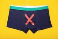 Men`s underpants with a red cross on a yellow background. Concept of male diseases, prostatitis and prostate adenoma, close-up