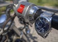 Men`s watches with two dials and an iron bracelet hang on the throttle handle of a chopper motorcycle Royalty Free Stock Photo