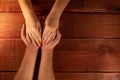 Men`s and women`s hands. Wife put her hands on her husband`s palms on background of a red textured wooden table. Concept of family