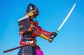 Men in samurai armour with sword on blue sky background.