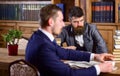 Men with serious faces in retro interior with bookshelves Royalty Free Stock Photo