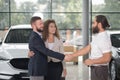 Men shaking hands, couple purchasing automobile.