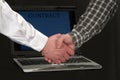 Men shaking hands in front of a laptop