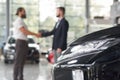 Men shaking hands in modern auto showroom. Royalty Free Stock Photo