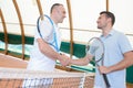 Men shaking hands over tennis court net Royalty Free Stock Photo