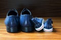 Men shoes and children sneakers side by side on the wooden floor