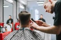 A man sits in a chair in a barbershop and makes a haircut with a professional barber. Hairdresser trims client with a beard