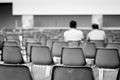 Men sitting on empty chairs