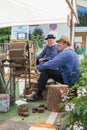 Men sitting next to an ancient machine to thresh grain