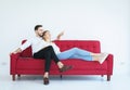 Man sitting on red sofa with woman and hand pointing out the window in living room at house,Happy and smiling,Positive attitude em Royalty Free Stock Photo