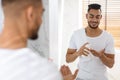 Men Skincare. Handsome Young Arab Man Using Aftershave Lotion In Bathroom Royalty Free Stock Photo