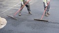 Men Smooting Freshly Poured Asphalt with Rakes