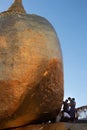 Men sticking gold leafs to the Kyaiktiyo Pagoda - Golden rock. Sacred buddhist pilgrimage site. Women not allowed to touch rock.