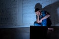 Men suffering Internet cyber bullying sitting alone with computer feeling hopeless