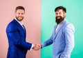 Men in suits businessmen hold hands in handshake. Businessmen with unshaven smiling faces shaking hands pink background