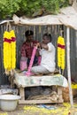 Men threading colourful flower garlands. These flowers are offered to the gods in the temples