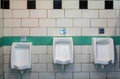 Men in toilet room urinals in an building for men only, white urinals in men's bathroom, white ceramic urinals Royalty Free Stock Photo