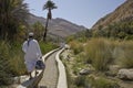 Men walking along water channel in Wadi Bani Khalid, Oman