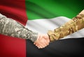 Men in uniform shaking hands with flag on background - United Arab Emirates